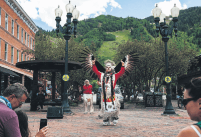 Traditional dancer performing in an scenic outdoor plaza with mountains in the background.